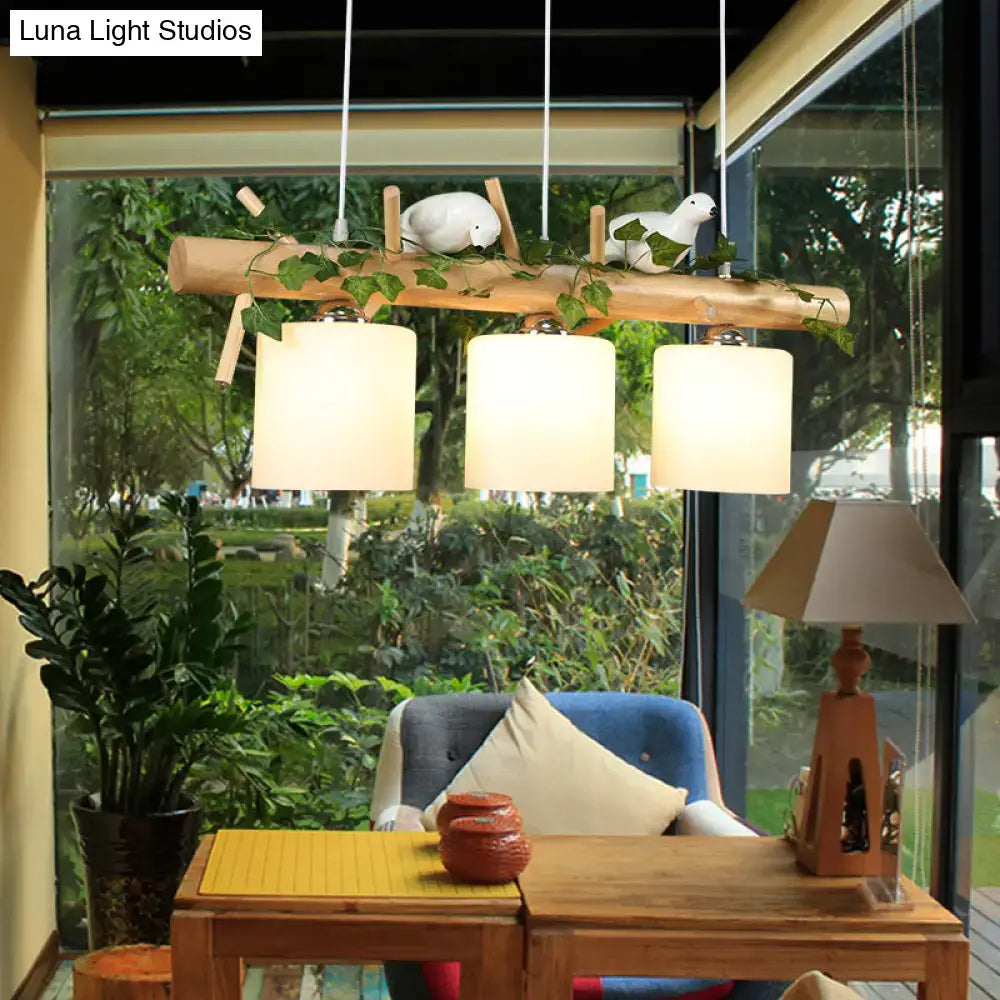DecorBites™ modern wood linear island lighting with natural wood branch, three off-white shades, and decorative maple leaf plant figurines