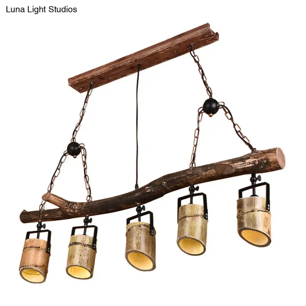 Rustic wood linear island pendant light with five bamboo cylinder shades and black metal fixtures suspended by chains