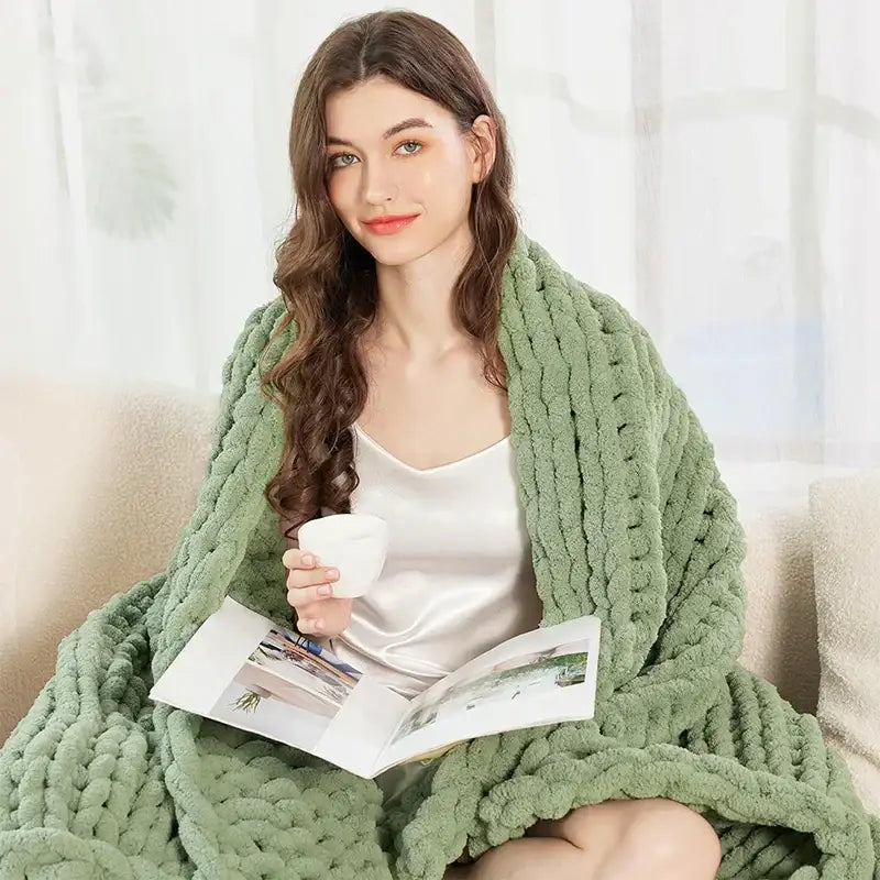 A sage green chunky knit cozy autumn fleece blanket draped over a woman’s shoulders by decorbites