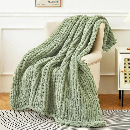 A sage green chunky knit fleece blanket draped over a chair featuring decorbites cozy autumn fleece design