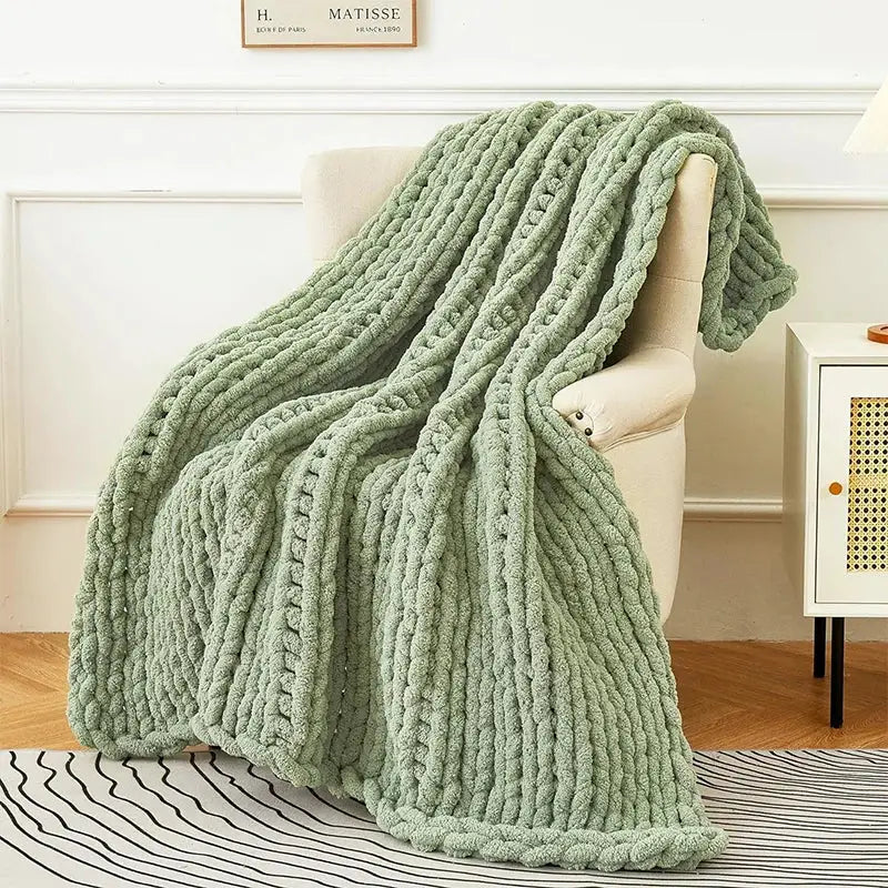 A sage green chunky knit fleece blanket draped over a chair featuring decorbites cozy autumn fleece design