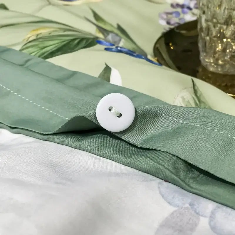 White round button with two holes sewn onto sage green fabric of decorbites 1400tc egyptian cotton bedding set