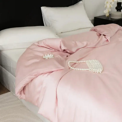 A delicate pearl-embellished clutch rests on a sage green double layer satin queen duvet set in bedroom bedding