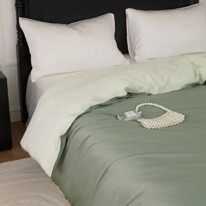 A delicate pearl-embellished handbag with transparent glass body and heart handle rests on a sage green double layer satin queen duvet set