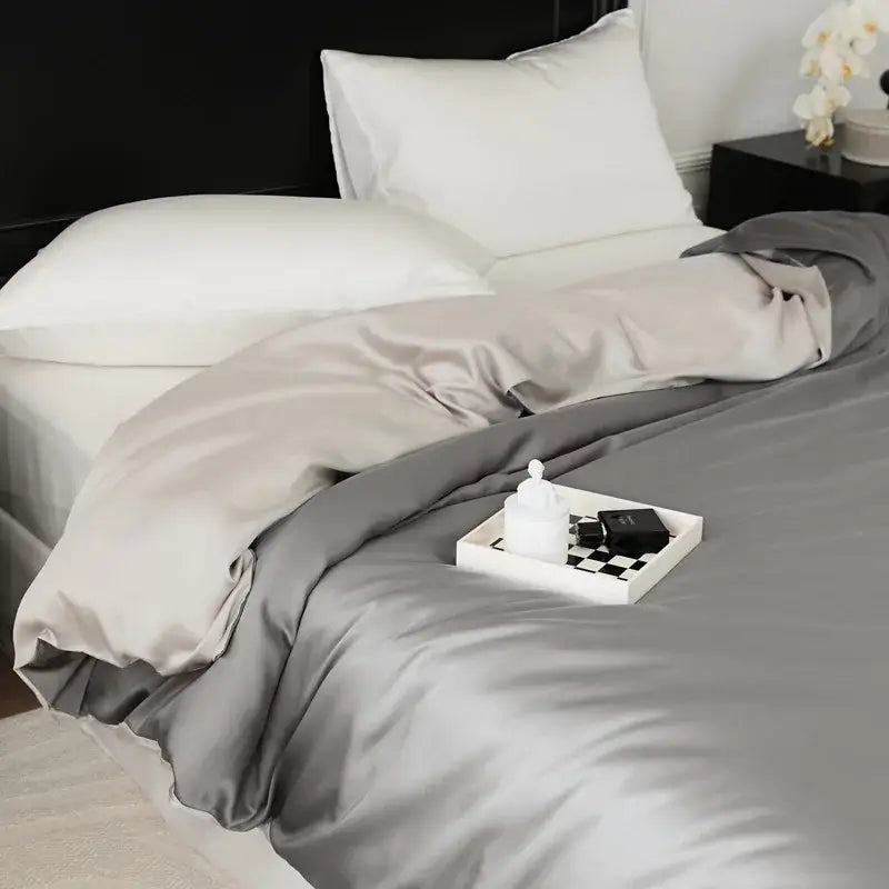 Silk duvet cover in soft gray with subtle sheen draped over white pillows in sage green double layer satin queen duvet set