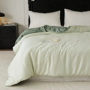Soft sage green double layer satin queen duvet set with matching pillowcase elegantly draped over the bed