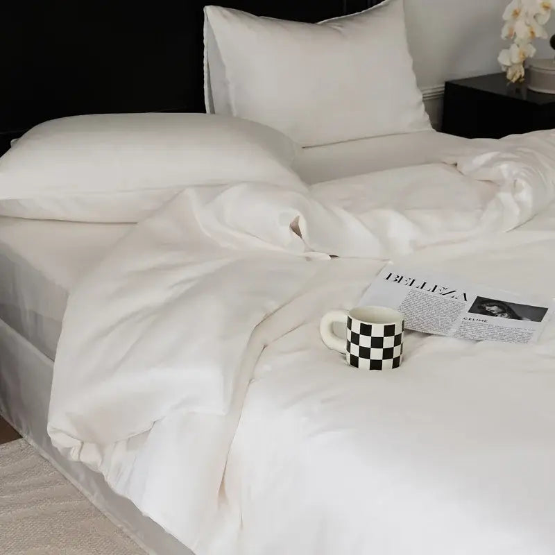 A white ceramic mug with a black and white checkered pattern next to a sage green double layer satin queen duvet set