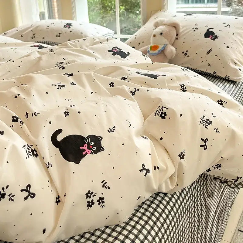 Sage green grid print cotton bedding set with cream duvet cover featuring a playful black cat and floral patterns