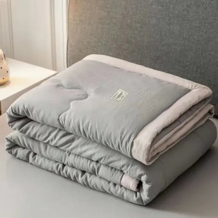 A soft folded gray cooling cotton quilt with cream inner lining and decorbites cooling cotton label on top surface