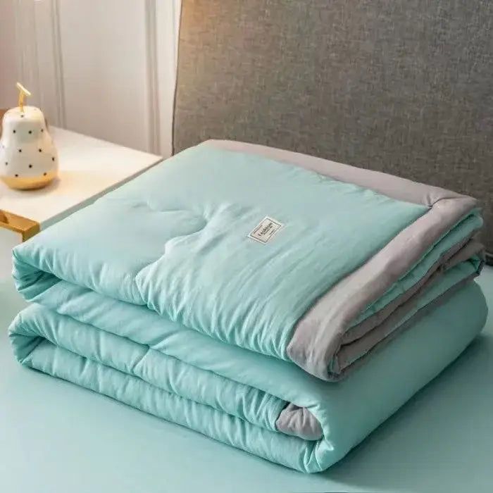A soft mint green decorbites cooling cotton quilt with gray edges and subtle stitching for bedroom use