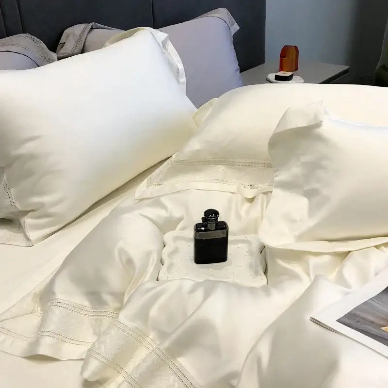 A sleek black perfume bottle with silver cap on cream satin bedding set featuring decorbites 1000tc lyocell fibre