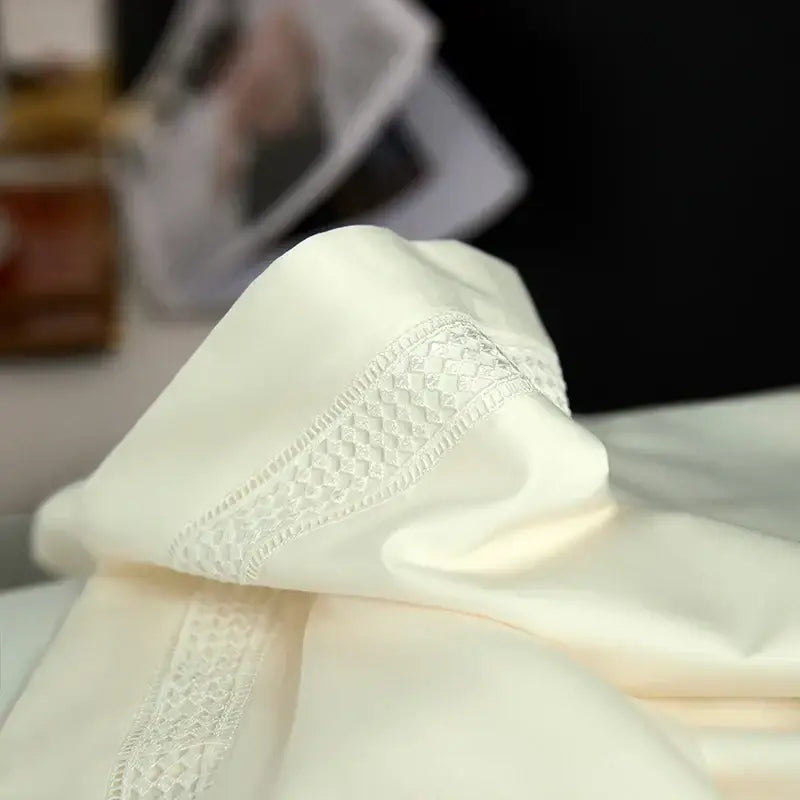 Cream-colored satin duvet cover set with delicate white lace trim and woven diamond pattern in egyptian cotton