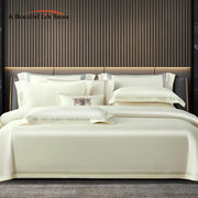 Cream-colored satin duvet cover set with subtle gold trim and embroidered pillow made of egyptian cotton bedding