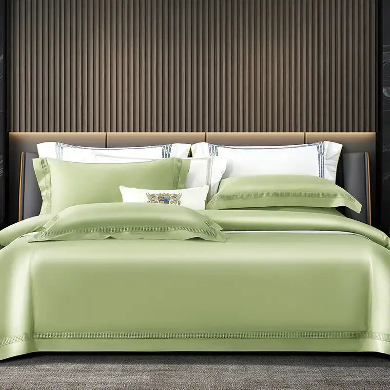 Luxurious sage green satin duvet cover set with elegant beaded trim and embroidered crest pillow sham in cream and gold