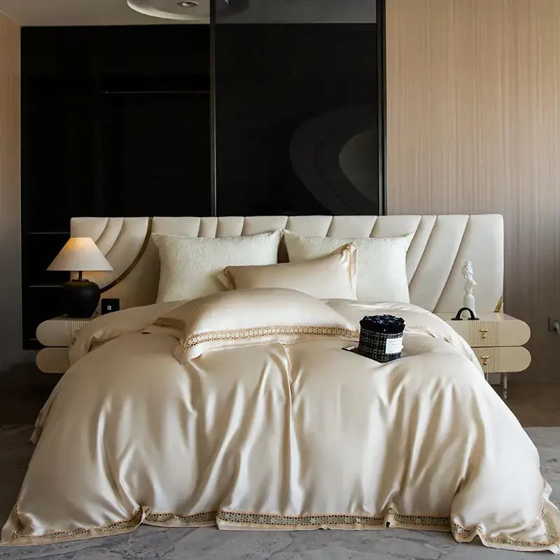 Cream-colored satin duvet cover set with gold-toned embroidered trim for elegant bedroom bedding