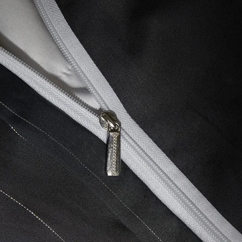 Silver textured zipper pull on white zipper track of dark gray satin duvet cover bedding set with silver pinstripes