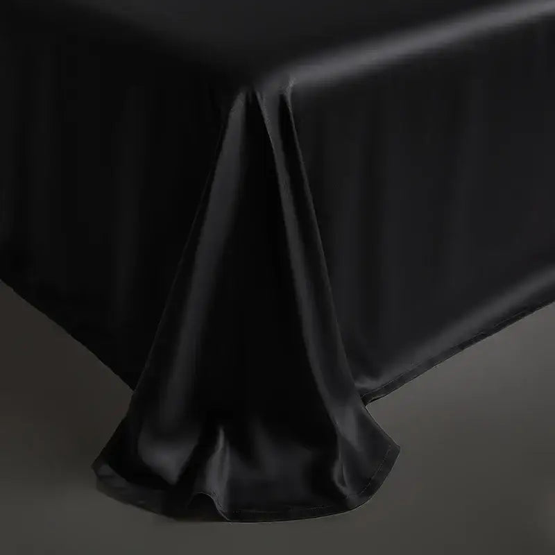 Black satin tablecloth with smooth glossy finish and elegant draping complementing dark gray duvet cover bedding set