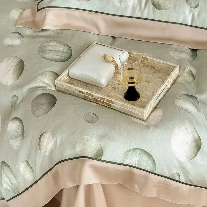 Beige mosaic-trimmed serving tray holding a white pillow and glass in satin light blue and pink egyptian cotton bedding set bedroom