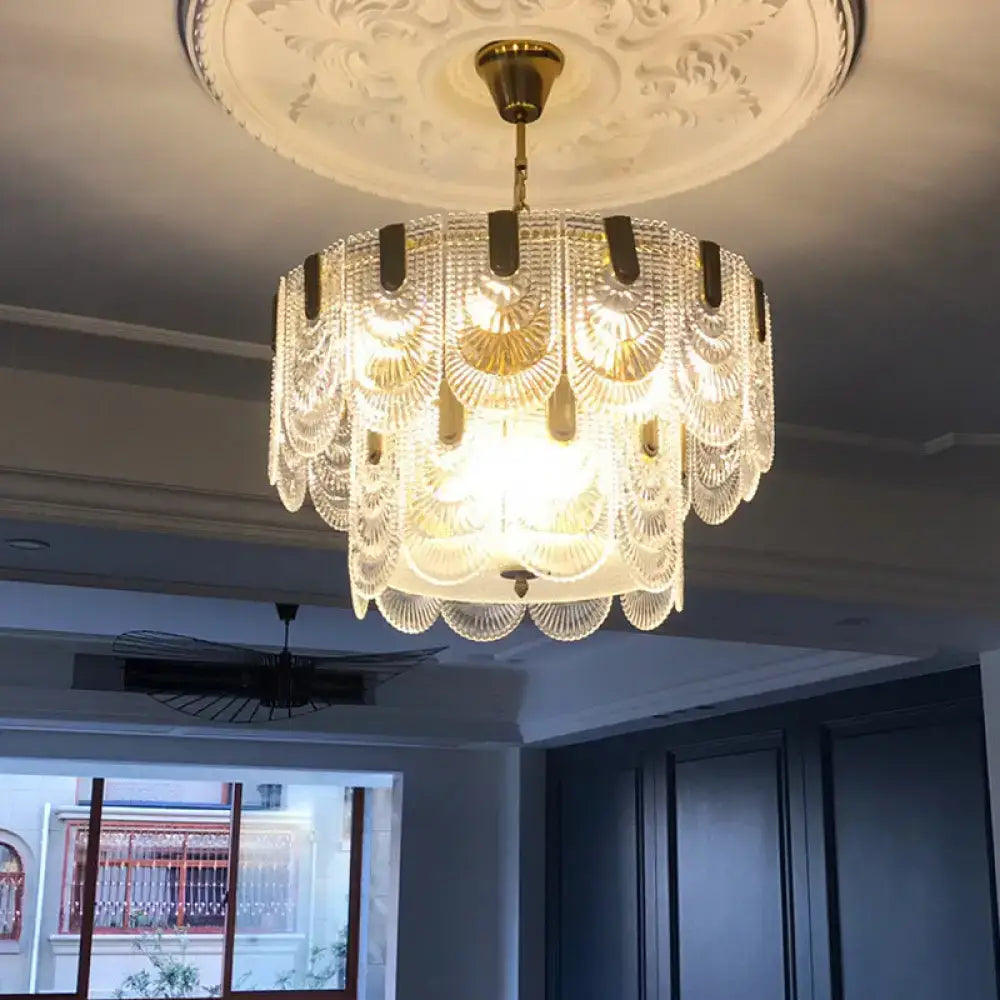 A tiered brass decorbites scalloped clear textured glass drop lamp chandelier with gold accents and a decorative ceiling medallion