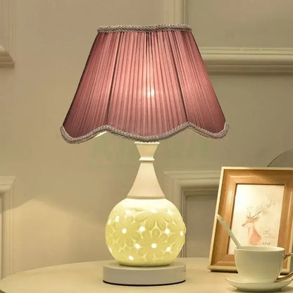 A soft pink pleated lampshade with scalloped edge and silver trim on a white floral decorbites ceramic led desk lamp base