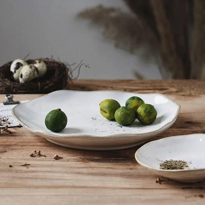 Scalloped white ceramic dinner plate set by decorbites holding green limes for elegant dining tableware use
