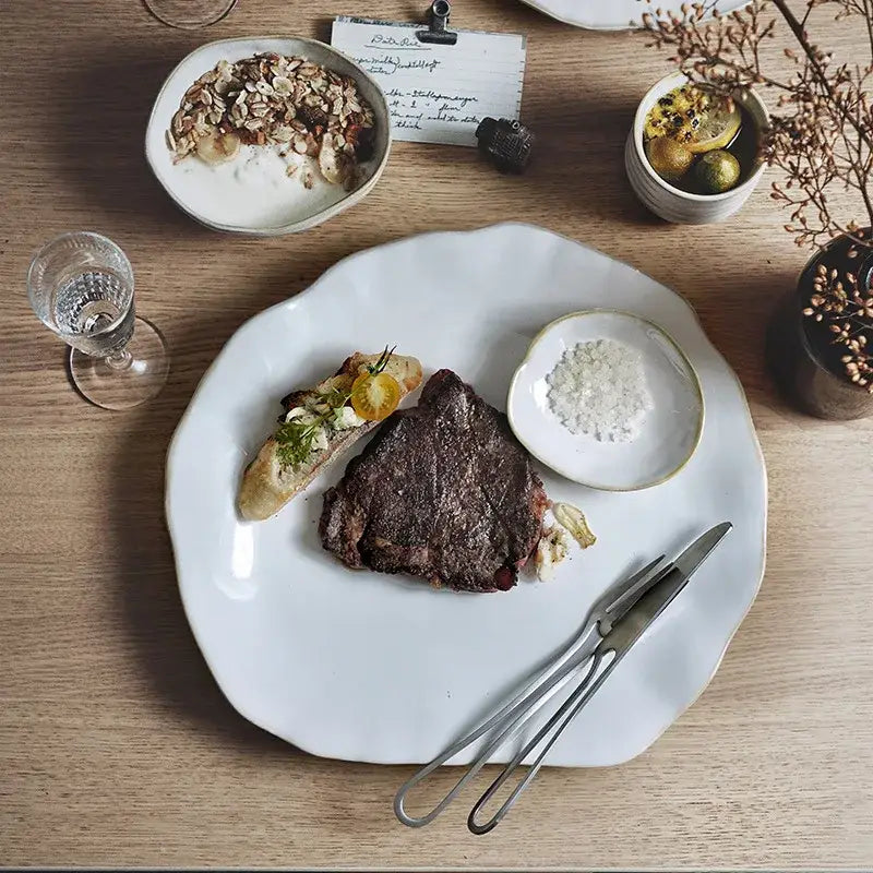 Scalloped white ceramic dinner plate set featuring a grilled steak bread slice and salt bowl for dining decorbites ceramic dinner