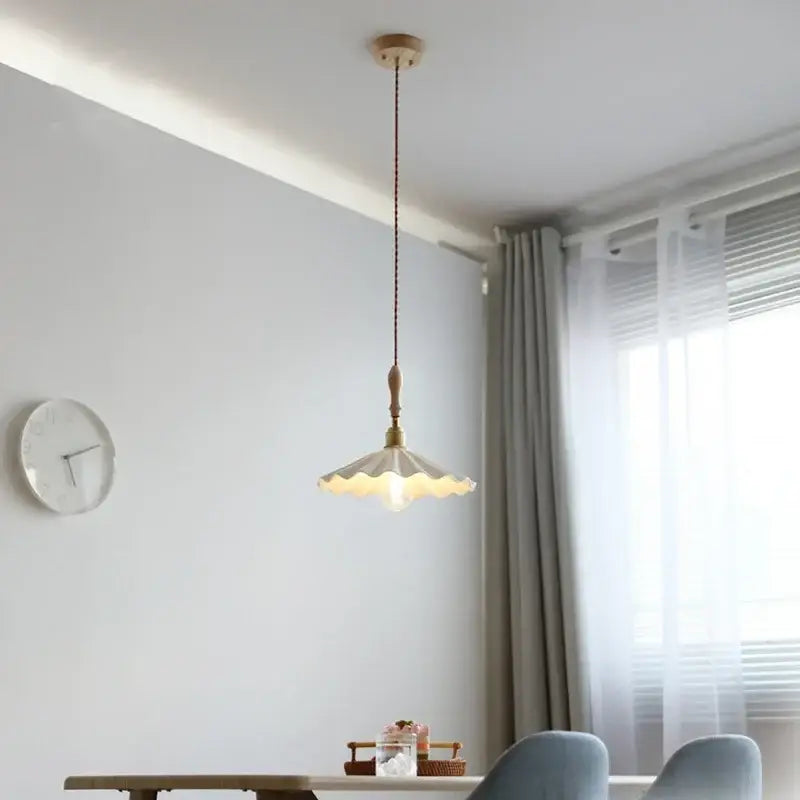 A cream-colored scalloped ceramic led pendant light with brass accents hanging from a wooden fixture for dining room decorbites ceramic led