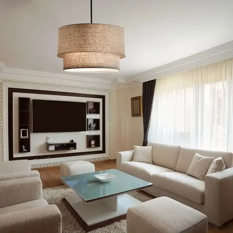 Beige cylindrical Scandinavian pendant light with double linen fabric shade hanging in dining room ceiling