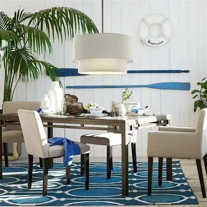 Beige upholstered dining chairs with dark wooden legs under a scandinavian double linen fabric pendant light dining room setup