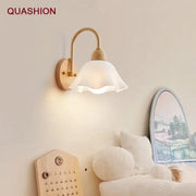A minimalist scandinavian wall lamp with a white frosted glass shade, brass arm, and cream led wooden base