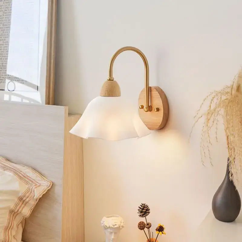 A warm-toned brass wall lamp with a wooden base and cream led frosted glass shade for bedroom decorbites cream led