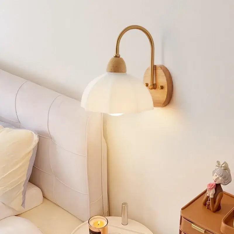 A warm-toned brass wall lamp with cream led frosted glass shade and wooden mounting plate for bedroom decorbites cream led