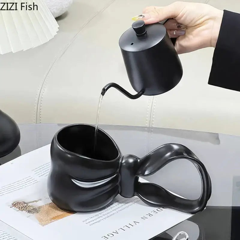 Black ceramic coffee mug with sculpted bowknot handle paired with decorbites bowknot ceramic teapot for tea serving