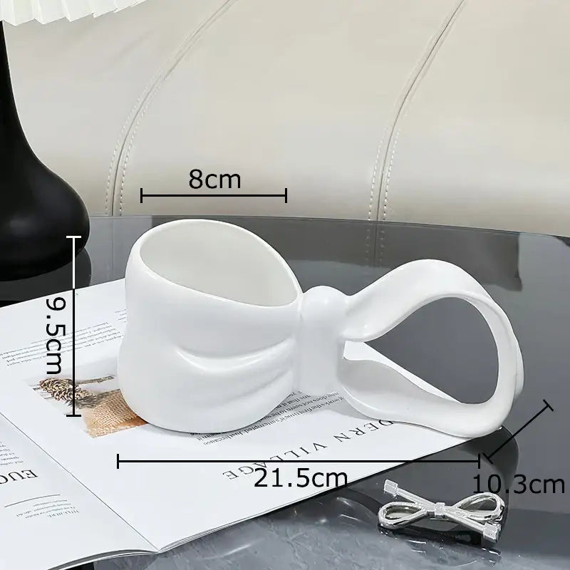 White ceramic bowknot ceramic coffee mug by decorbites shaped like a sculpted bow for kitchen tea use