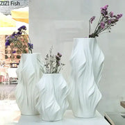 Sculpted white ceramic vase set by decorbites with flowing surfaces holding dried purple flowers for bedroom decor