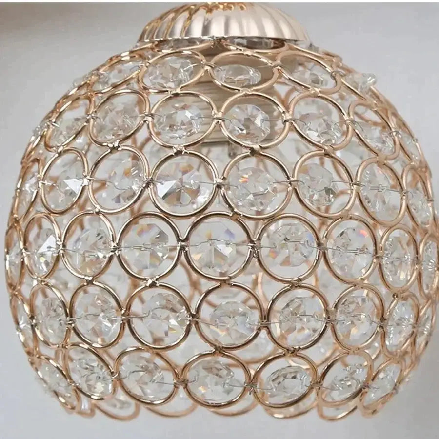 Sculptural gold violinist crystal wall lamp featuring a spherical gold-toned crystal wall sconce with interlocking rings
