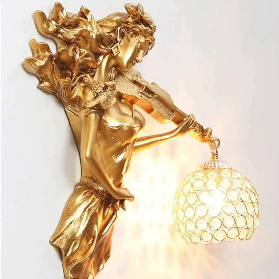 Sculptural gold wall lamp featuring a violinist figure with flowing robes and an ornate crystal wall globe lampshade