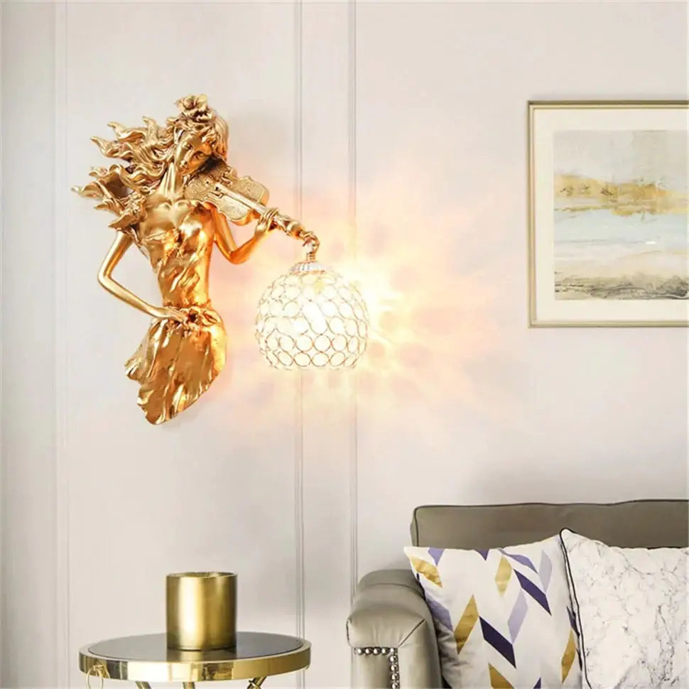 Golden sculptural wall lamp featuring a violinist figure with flowing hair and an ornate crystal globe light fixture