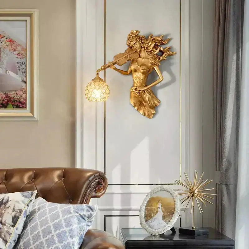 Gold sculptural wall lamp featuring a violinist figure with flowing hair holding an ornate crystal wall lamp