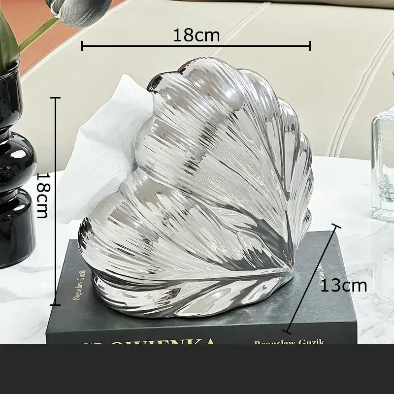 Shiny silver shell-shaped tissue box holder with intricate ridged texture in decorbites heart feather ceramic design