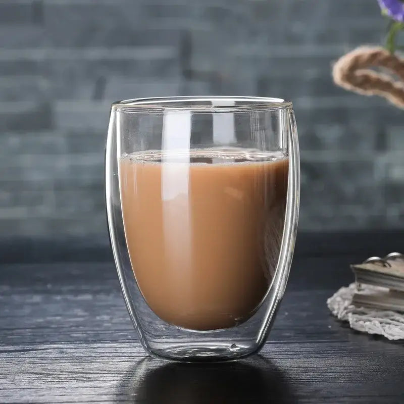 Set of 3 clear double wall glass cup tumblers with one filled with a warm creamy brown beverage