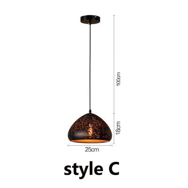 Set of 4 black and gold etched iron pendant light fixtures with dark speckled ceramic shades and warm amber glow for dining room