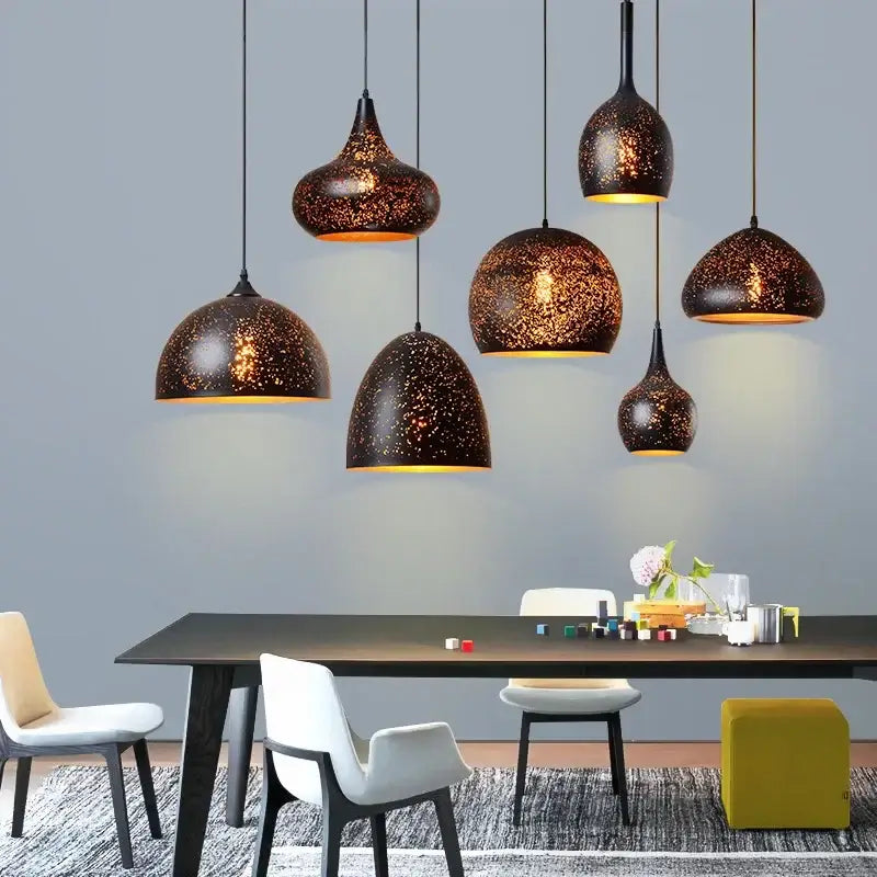 Set of seven black speckled iron pendant light fixtures with warm gold interiors for dining room lighting