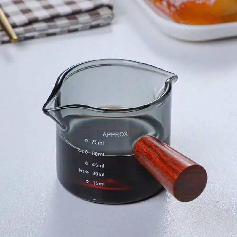 A sleek dark gray glass measuring cup with polished wooden handle and clear volume markings from decorbites glass double set