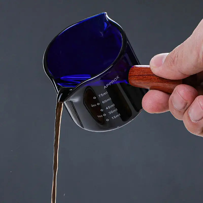 Deep blue glass measuring cup with wooden handle and double mouth design marked in milliliters and ounces decorbites glass double