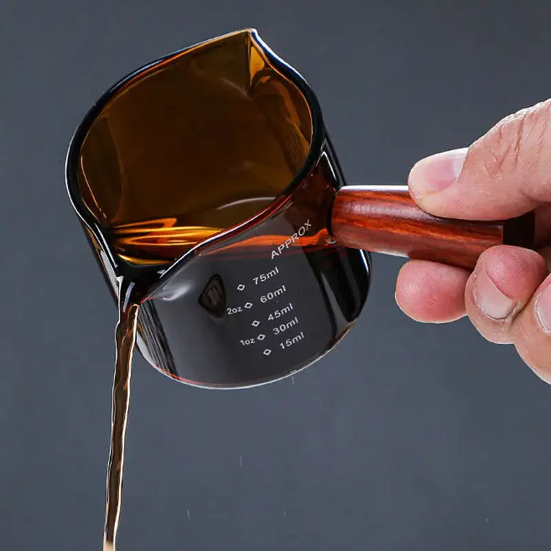 A sleek amber glass measuring cup with a polished wooden handle and double mouth design from decorbites glass double set