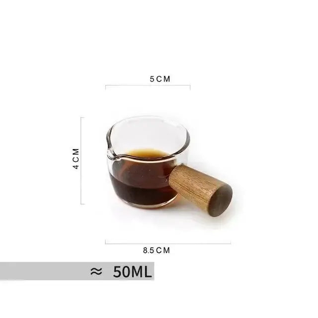 A clear glass measuring cup with a wooden colored handle layer filled with dark liquid for kitchen use