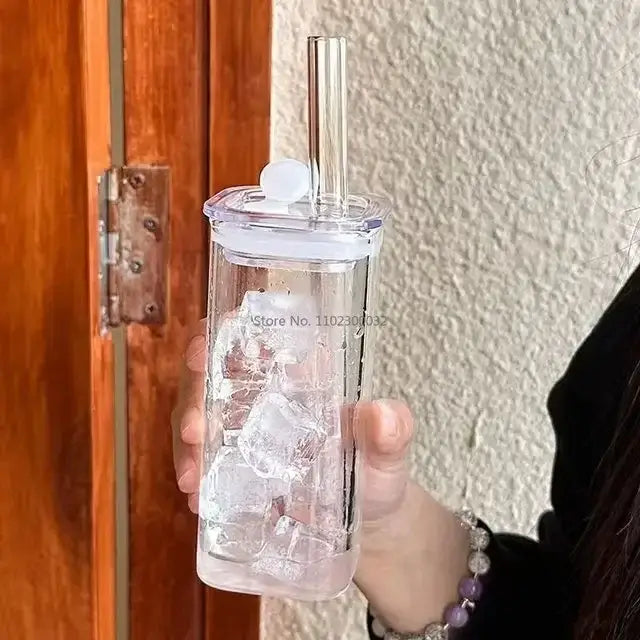 Clear plastic tumbler with white lid, silver straw, and ice cubes featuring colored handle layer for kitchen use