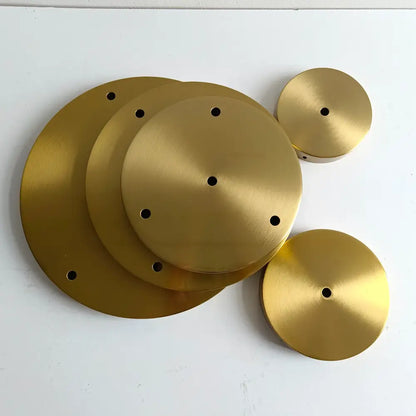 Set of five brushed gold-colored circular metal plates with central and perimeter holes for brass ceiling plate lamp bases