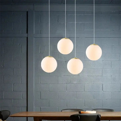 Four frosted glass ball pendant lights with gold fixtures from decorbites hanging against dark gray wall for living room decor